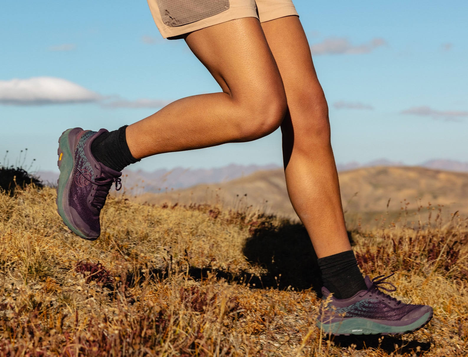 Woman running on a scenic mountain trail wearing women's trail running shoes from Topo Athletic Ultraventure 4, designed for comfort and durability